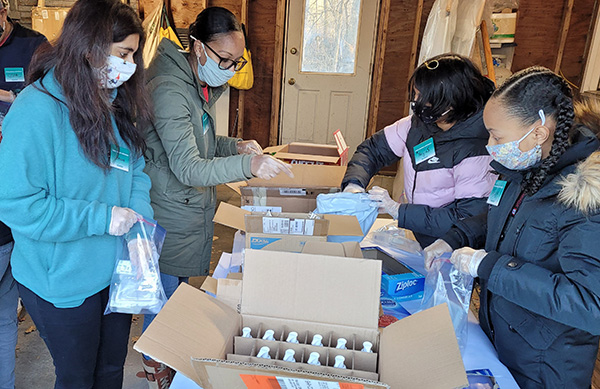 12/12/21 Two mothers and their daughters wearing masks and gloves and cclad in winter coats pack toiletries and other needed supplies for street outreach to homeless people in Boston in the winter