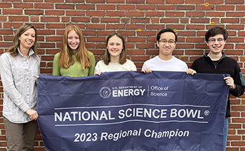 2023 Maine High School Science Bowl Champion: Cape Elizabeth High School team (coach Amy de Vries (left) pictured with four students (alphabetically by last name: Ainsley Fremont, Ben Le, Zoe Matzkin, and Trevor Oakley) holding their 